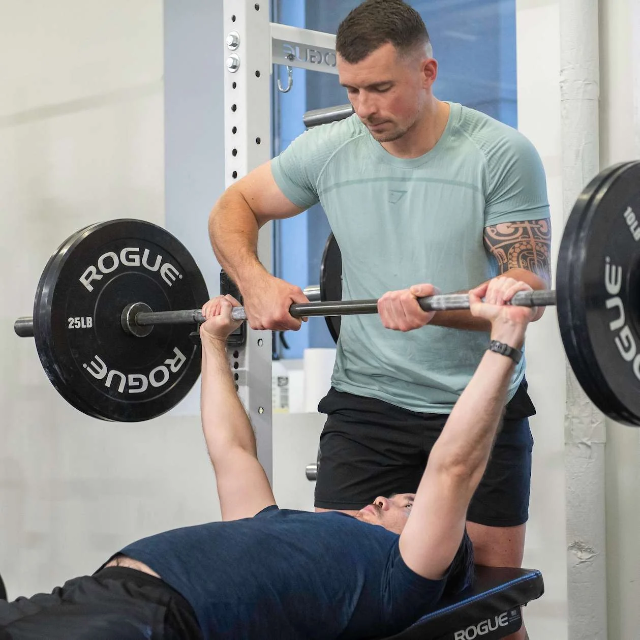 Romain guiding a male client through a barbell bench press